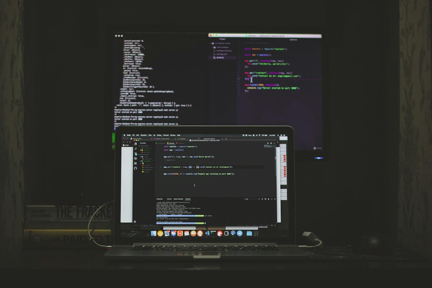Laptop e monitor esterno con codice su una scrivania.