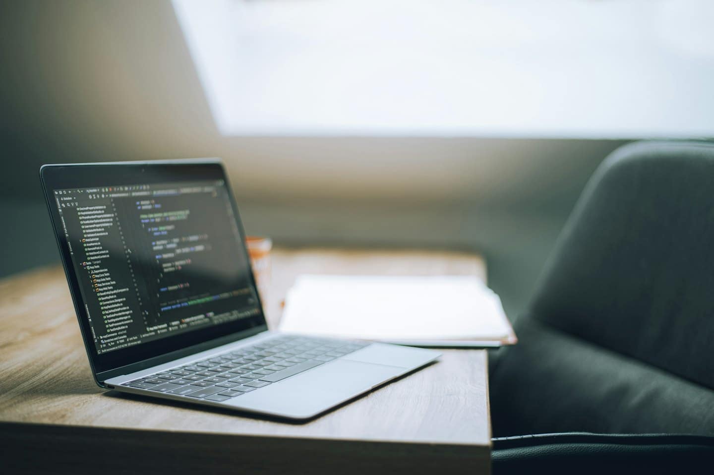 Un laptop con codice di programmazione su una scrivania di legno.