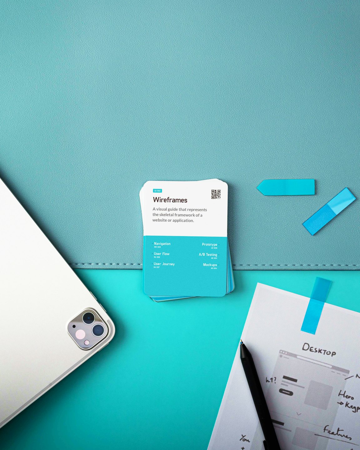 Tablet e carte per il design UX/UI disposti su uno sfondo verde acqua.